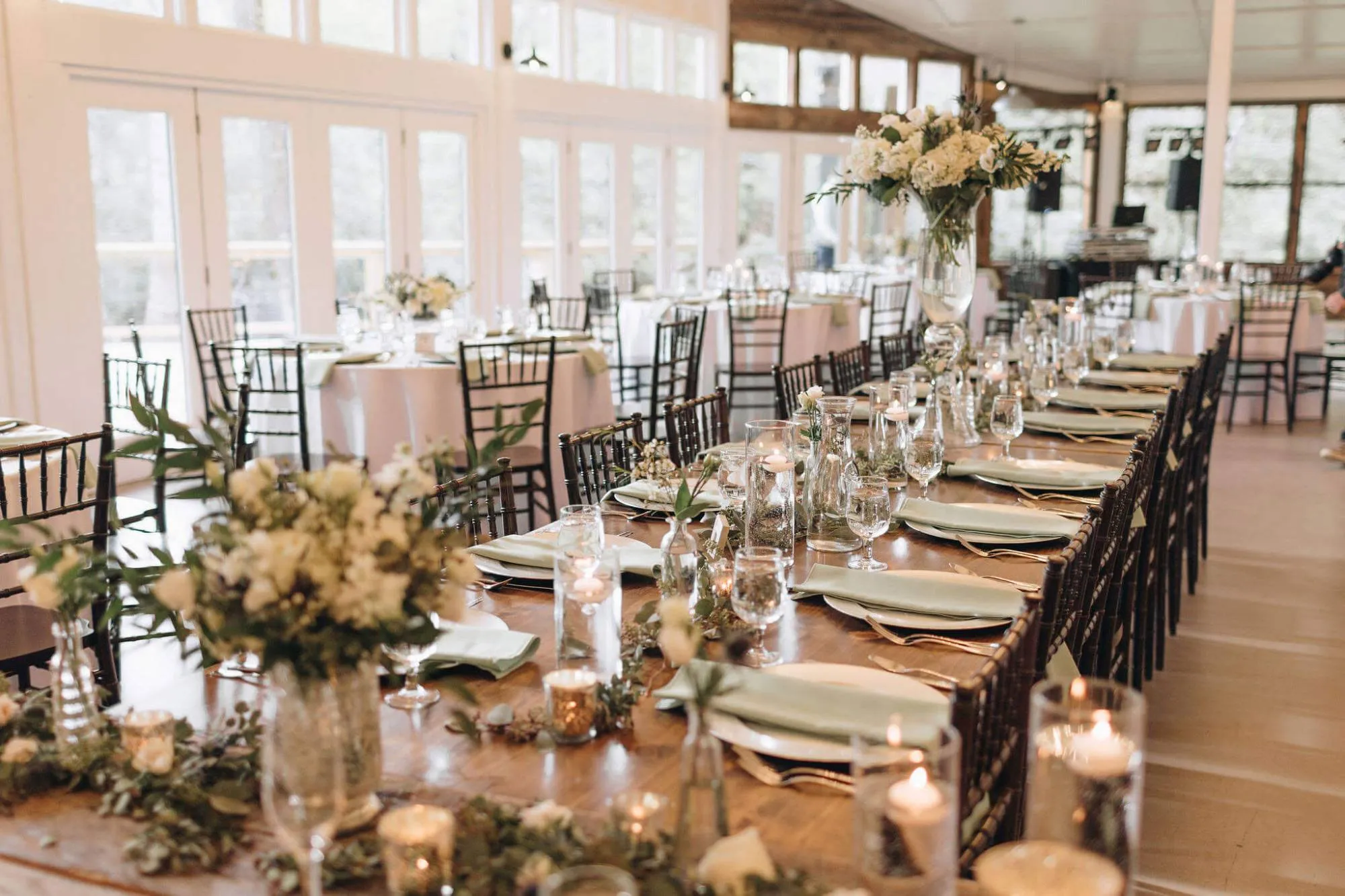 The Barn Pavilion set for a wedding dinner — long farm tables, candles, and florals